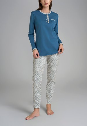 Top blu a maniche lunghe con scollatura abbottonata e tasca. Pantaloni bianchi con un motivo geometrico blu e beige. Entrambi sono realizzati in tessuto morbido.