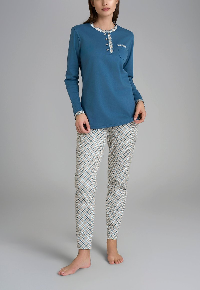Top blu a maniche lunghe con scollatura abbottonata e tasca. Pantaloni bianchi con un motivo geometrico blu e beige. Entrambi sono realizzati in tessuto morbido.