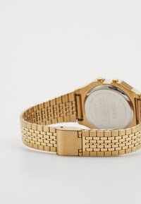 Goldenes Metallarmbanduhr mit einem Mesh-Armbanddesign, das ein rechteckiges Gehäuse und einen glatten Verschluss bietet. Die Rückseite zeigt die Marken- und Modelldetails.