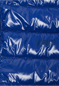 Blå puffer vest laget av glanset, quiltet materiale med horisontale sømmer og en subtil logo. Jevn tekstur med en skinnende finish.
