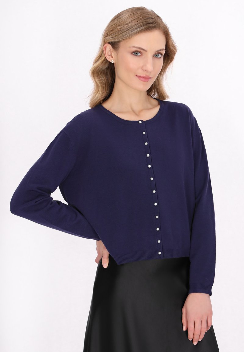 Pulover scurt de culoare bleumarin, confecționat din material tricotat, cu decolteu rotund, mâneci lungi și nasturi decorativi din perlă pe partea din față.