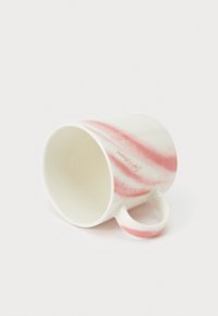 Taza de cerámica con base blanca y rayas onduladas rosas, con cuerpo redondo y asa pequeña. El interior es liso y sencillo.