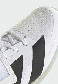 Weiße Sportlichkeit mit einer strukturierten Oberseite, schwarzen Akzenten und einem auffälligen "Strength in Numbers"-Detail an der Seite.