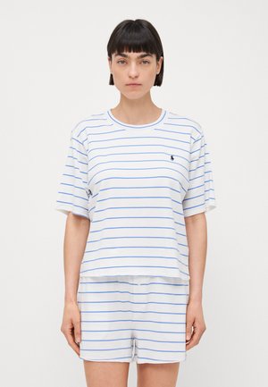 Weiß gestreiftes T-Shirt mit blauen Linien und kurzen Ärmeln, kombiniert mit weißen Shorts. Das Material wirkt weich und lässig und hat ein Logo-Detail.