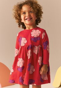 Rochie roșie cu mâneci lungi, având modele de flori roz și mov. Fabricată din bumbac, are o talie strâmtă și o textură moale.