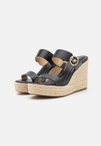 Sandale negre cu toc wedge din piele, cu două bretele late și un accent cu logo rotund. Platforma din jute texturat adaugă un contrast pielii netede.