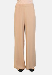 Beige wijde broek met een gladde, gestructureerde afwerking en een elastische tailleband. Het ontwerp heeft lange broekspijpen en geen zichtbare hardware.