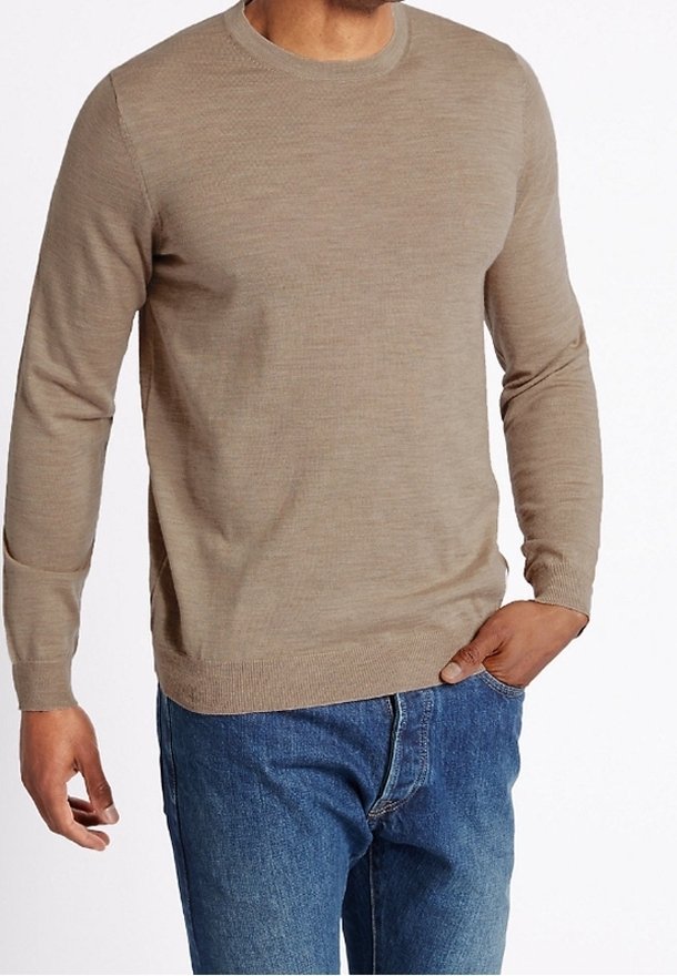 Béžový svetr s dlouhým rukávem z texturované pleteniny, s kulatým výstřihem a žebrovanými manžetami, v kombinaci s modrými džínami.