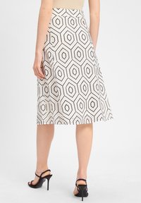 A knee-length skirt featuring a geometric hexagonal pattern in black on a cream background, made from a smooth fabric, with a fitted waist.