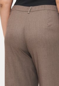 Brown dress pants with a textured finish, featuring an elastic waistband and a straight leg cut. No visible pockets or hardware details.