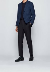 Marynarski blazer w kratę. Ciemna koszula pod spodem. Slim fit czarne spodnie i czarne skórzane buty eleganckie. Dopasowany krój, gładki materiał.