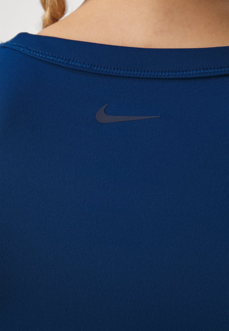 Marineblauw sportshirt van gladde, stretchstof met een klein, zwart Nike-logo op de achterkant dichtbij de halslijn.