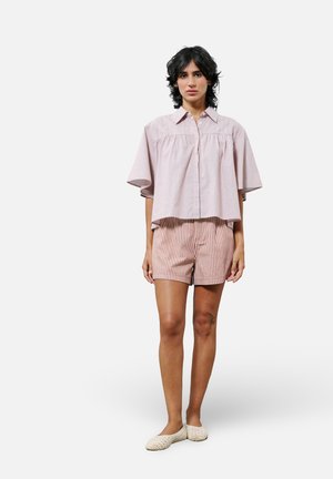 Rosa gestreifte Kurzarmbluse mit Knopfverschluss, kombiniert mit gestreiften Shorts in einem ähnlichen Farbschema. Leichter Stoff und lockere Passform.