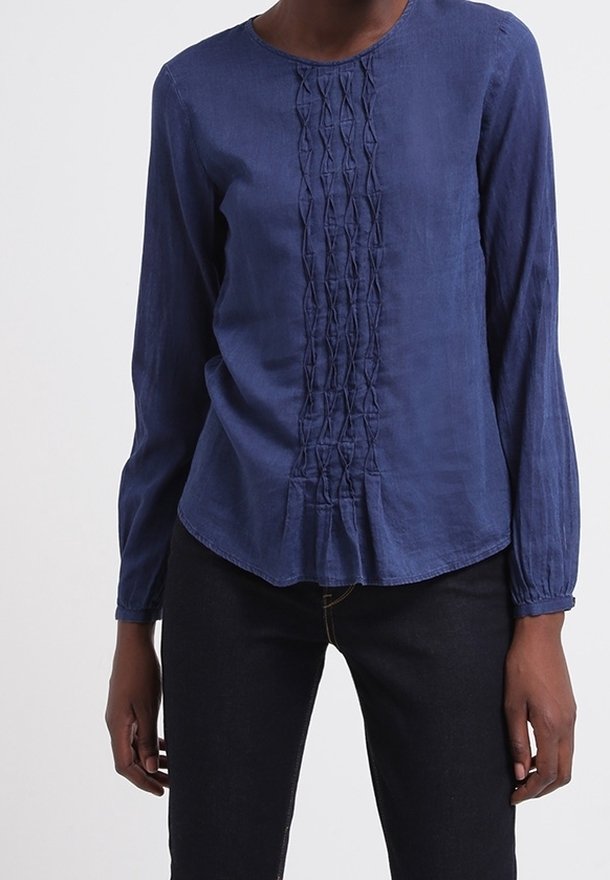 Marinblå blus med lång ärm och rund halsringning, med texturerade vertikala veck framtill och en rundad fåll.