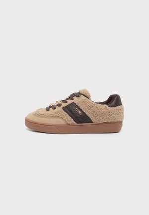 Beiger und brauner Sneaker mit Plüschtextur, dunkelbraunen Schnürsenkeln und einem dunklen Bereich mit kleinem metallischem Markenlogo auf einer flachen Sohle.
