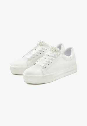 Baskets blanches en cuir avec des lacets plats et des accents en perles décoratifs. Texture lisse avec une semelle en caoutchouc et un design profil bas.