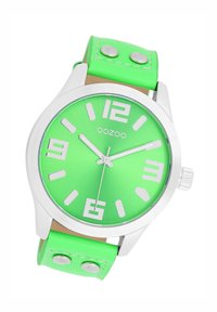Round green watch with a metallic silver case, large white numerals, and a bright green leather strap featuring silver studs.