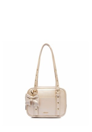Bolso rectangular beige con correas largas tachonadas, bolsillo delantero, detalles dorados y un llavero decorativo con lazo, sujeto a una correa.