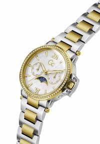 Montre-bracelet bicolore argent et or avec lunette en cristal, phases de lune, sous-cadrans jour et date, et cadran blanc texturé indiquant l'heure 10:10.