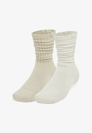 Pár kotníkových ponožek v světle béžové a krémové barvě, s žebrovaným lemem a hladkým tělem, zesílené části na špičce a patě.