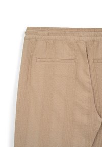 Pantalon beige texturé avec taille élastique et deux poches passepoilées arrière, présenté sur un fond blanc.