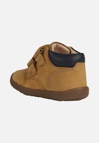 Stivale alla caviglia in pelle marrone con due cinturini in Velcro, punta arrotondata e accenti in navy a contrasto sul colletto. Suola in gomma per una buona aderenza.
