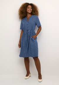 Modra obleka s kratkimi rokavi, z gumbom spredaj in pasom na vrvico; vsebuje cvetlični vzorec in stranska žepa; gladka tkanina.