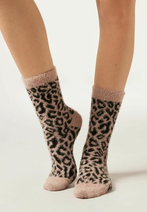 Pattesokker med leopardprint i et blødt, struktureret stof. Lys pink farve med sorte mønstre og fuzzy manchetter. Ankellængde med solid pink tå.