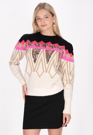 Maglione a maglia color crema con accenti neri, rosa e oro; presenta motivi geometrici e paillettes sul petto. Abbinato a una gonna nera.