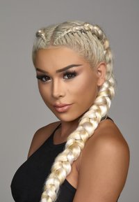 Longs cheveux blonds coiffés en une queue de cheval tressée, avec une texture lisse. Le sujet porte un haut sans manches noir devant un arrière-plan neutre.