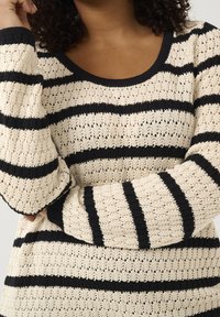 Pull en maille crème avec des rayures horizontales bleu marine, doté d'un col rond et d'un motif texturé à mailles ajourées. Manches longues.