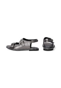 Metallisch silberne Sandalen mit zwei Schnallen, offenem Zeh und verstellbarem Riemen. Sie verfügen über eine kontrastierende schwarz-weiße gestreifte Sohle.