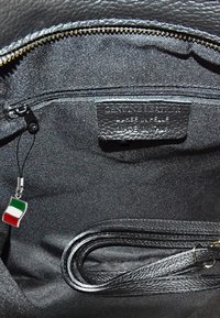 Zwarte leren handtasinterieur met een ritsvak, stoffen voering en een hanger met de Italiaanse vlag. Inclusief een platte schouderband en merklabel.