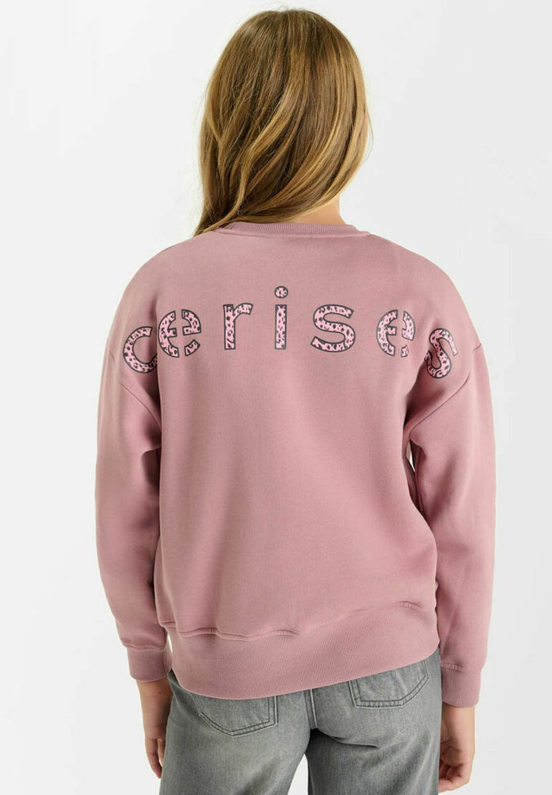 Roze sweatshirt met "cerises" in gestructureerde zwarte en roze letters op de achterkant. Voorzien van ribgebreide manchetten en zoom, gemaakt van zachte stof.