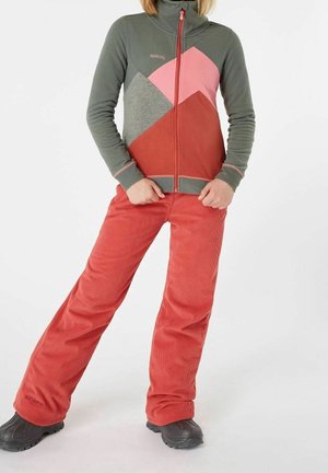 Fleece jacket in green, pink, and red with geometric patterns; paired with red corduroy pants. Black footwear with textured soles.