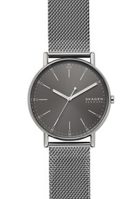 Skagen-kello, jossa on harmaa kellotaulu, hopeinen verkon hihna, minimalistinen muotoilu, tuntimerkit ja hoikat viisarit. Varustettu pyöreällä ruostumattomasta teräksestä valmistetulla kotelolla.