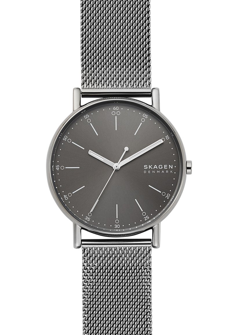 Skagen-kello, jossa on harmaa kellotaulu, hopeinen verkon hihna, minimalistinen muotoilu, tuntimerkit ja hoikat viisarit. Varustettu pyöreällä ruostumattomasta teräksestä valmistetulla kotelolla.