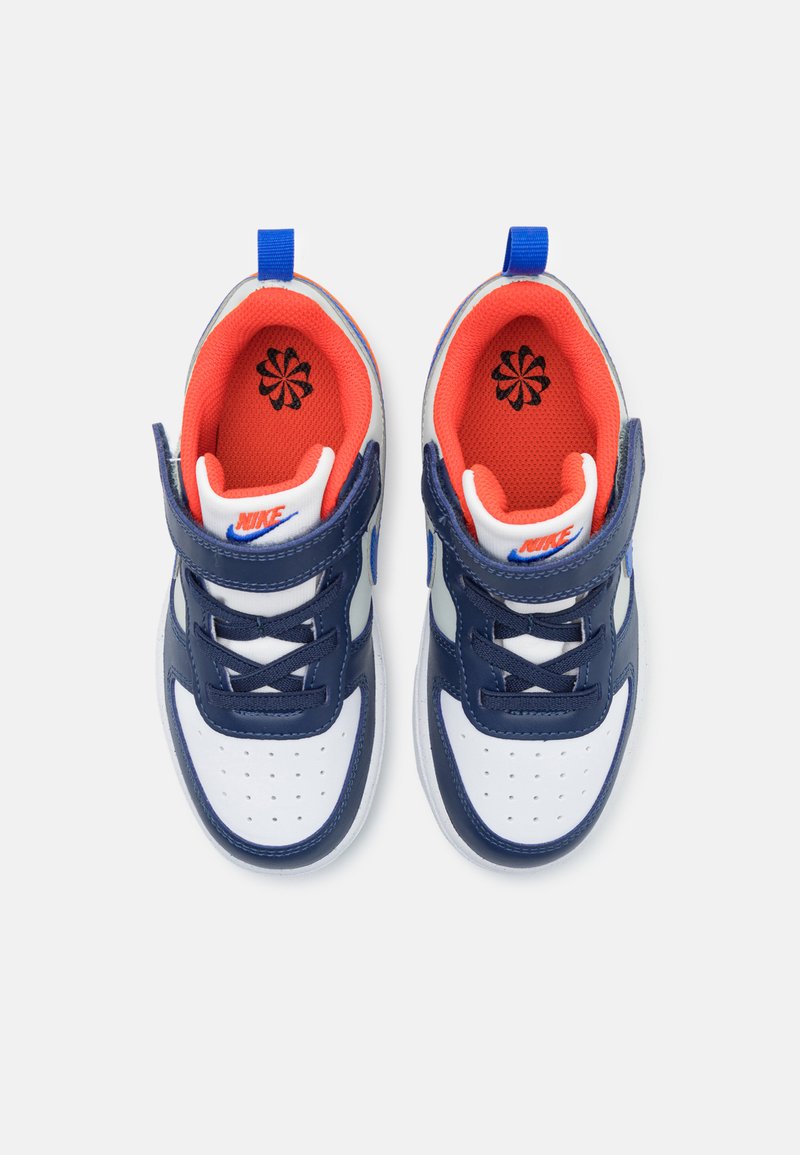 Nike-Sneaker mit einem Obermaterial aus weißem und marineblauem Leder, rotem gepolstertem Futter, weißer perforierter Zehenpartie und verstellbarem Riemen.