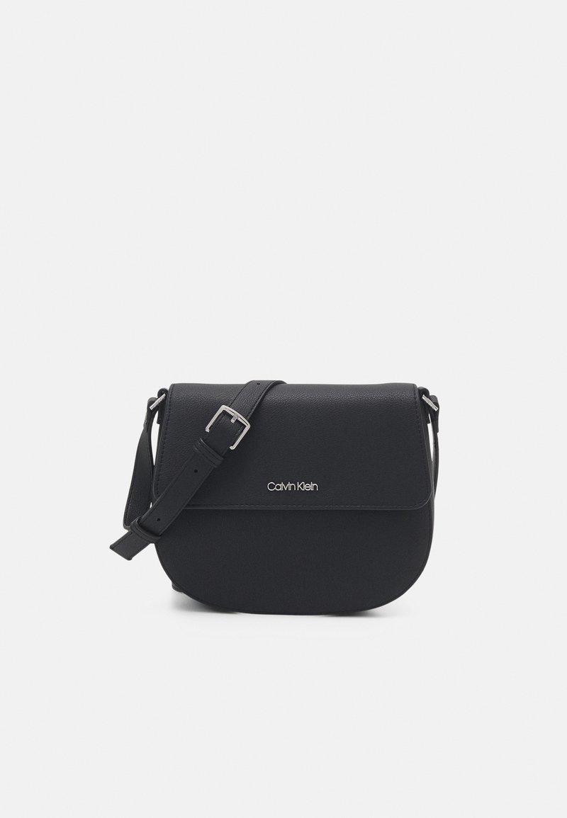 Sort crossbody-taske med klaplåge, lavet af tekstureret materiale. Har en justerbar rem og en sølvfarvet logo foran.