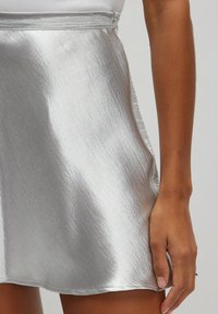 Zilveren metallic mini-jurk met een gladde, reflecterende textuur, zijrits en een strakke, A-lijn silhouet.