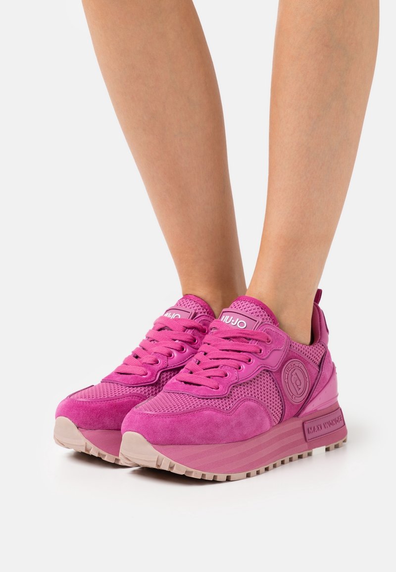 Baskets de sport roses en suède et mesh, dotées d'un col rembourré, d'accents de logo et d'une semelle en caoutchouc texturée.