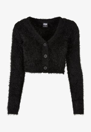 Schwarze flauschige, kurze Strickjacke mit langen Ärmeln, tiefem V-Ausschnitt und vorderem Knopfverschluss mit vier runden schwarzen Knöpfen.