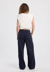 Losse crème top met korte mouwen, gecombineerd met marineblauwe wijde broekspijpen. Zachte stof en elastische tailleband op de broek.