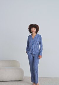 Blå och vita randiga pyjamaser i mjukt tyg som har en knäppbar överdel med krage och matchande raka byxor.
