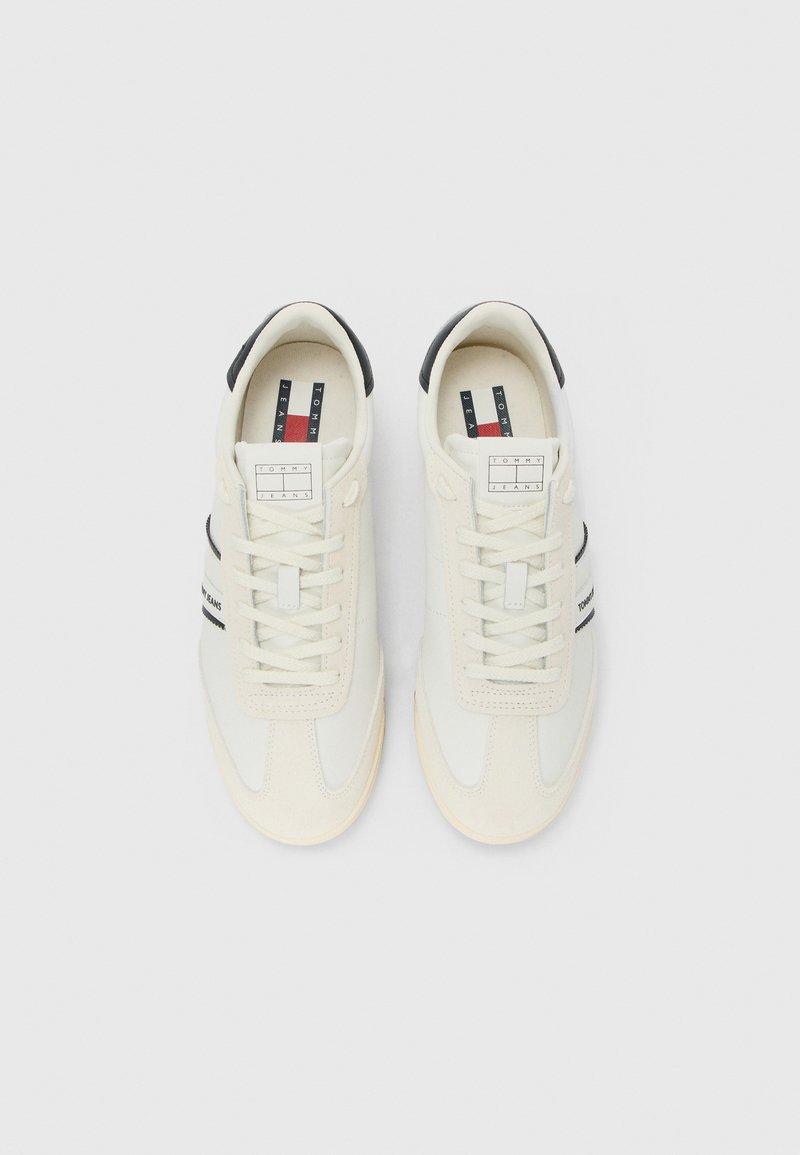 Une paire de baskets blanches Tommy Jeans avec des accents noirs au talon et un système de laçage, vue du dessus sur un fond blanc.