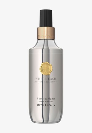 Bottiglia per profumo da casa in vetro trasparente con ugello spray nero e una fascia decorativa dorata. Presenta un emblema dorato e un'etichetta con testo nero sulla parte frontale.