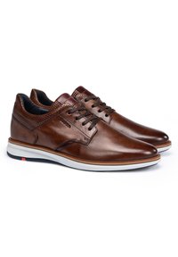 Braune Leder-Schnürschuhe mit perforierten Details, glatter Oberfläche, weißer Gummisohle und dezenten Kontrastnähten.