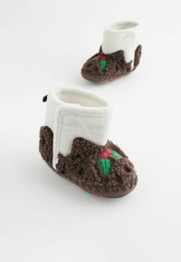 Flauschige braune Stiefel mit weißem Bund, verziert mit gestickten Stechpalmenblättern und roten Beeren. Weicher Stoff, abgerundete Form und flaches Design.