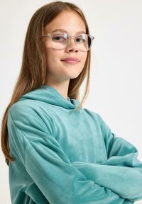 Turkusowa bluza z kapturem wykonana z miękkiego, teksturowanego materiału. Modelka ma długie włosy i nosi okrągłe, przejrzyste okulary.