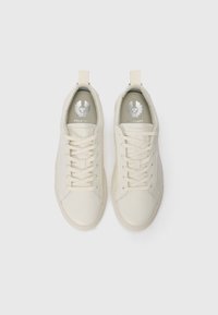 Beige lær sneakers med en glat finish, rund tå, elastiske snørebånd og en lille hækklap på hælen. Sølvlogo på indersålen.